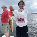 A smiling child proudly holding a redfish caught during a fun-filled fishing charter with Southern Escape Charters.